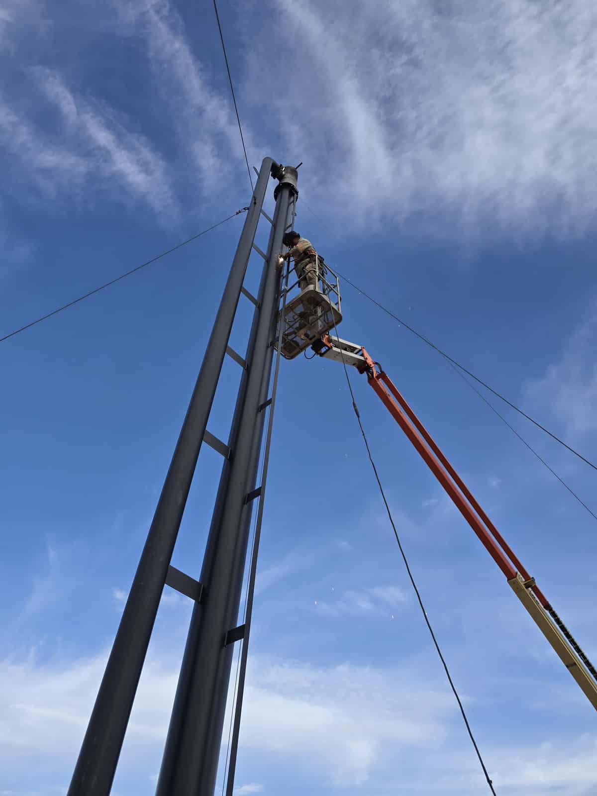 ROS technician welding on a flare stack from a man-lift