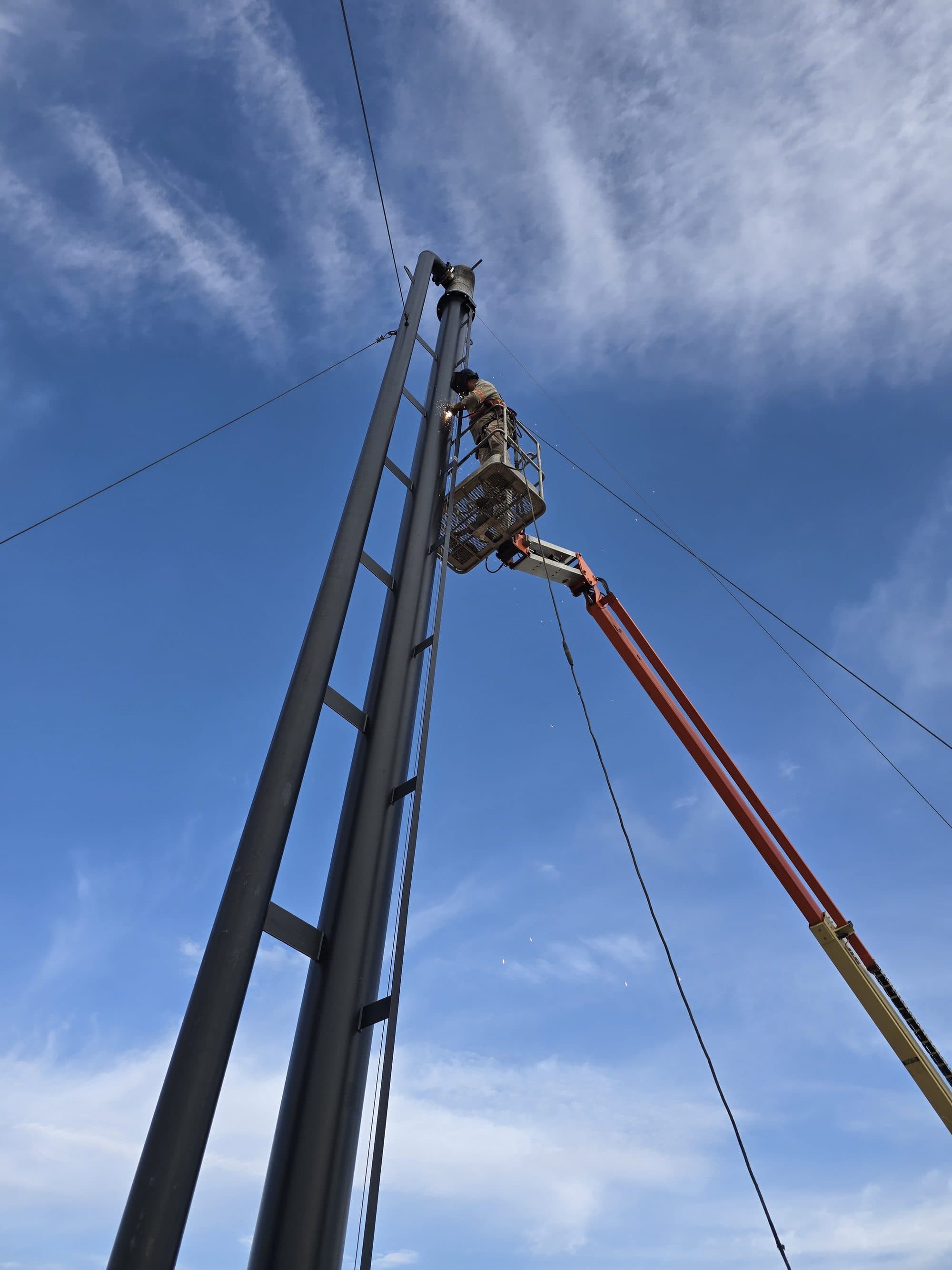 ROS technician welding on a flare stack from a man-lift