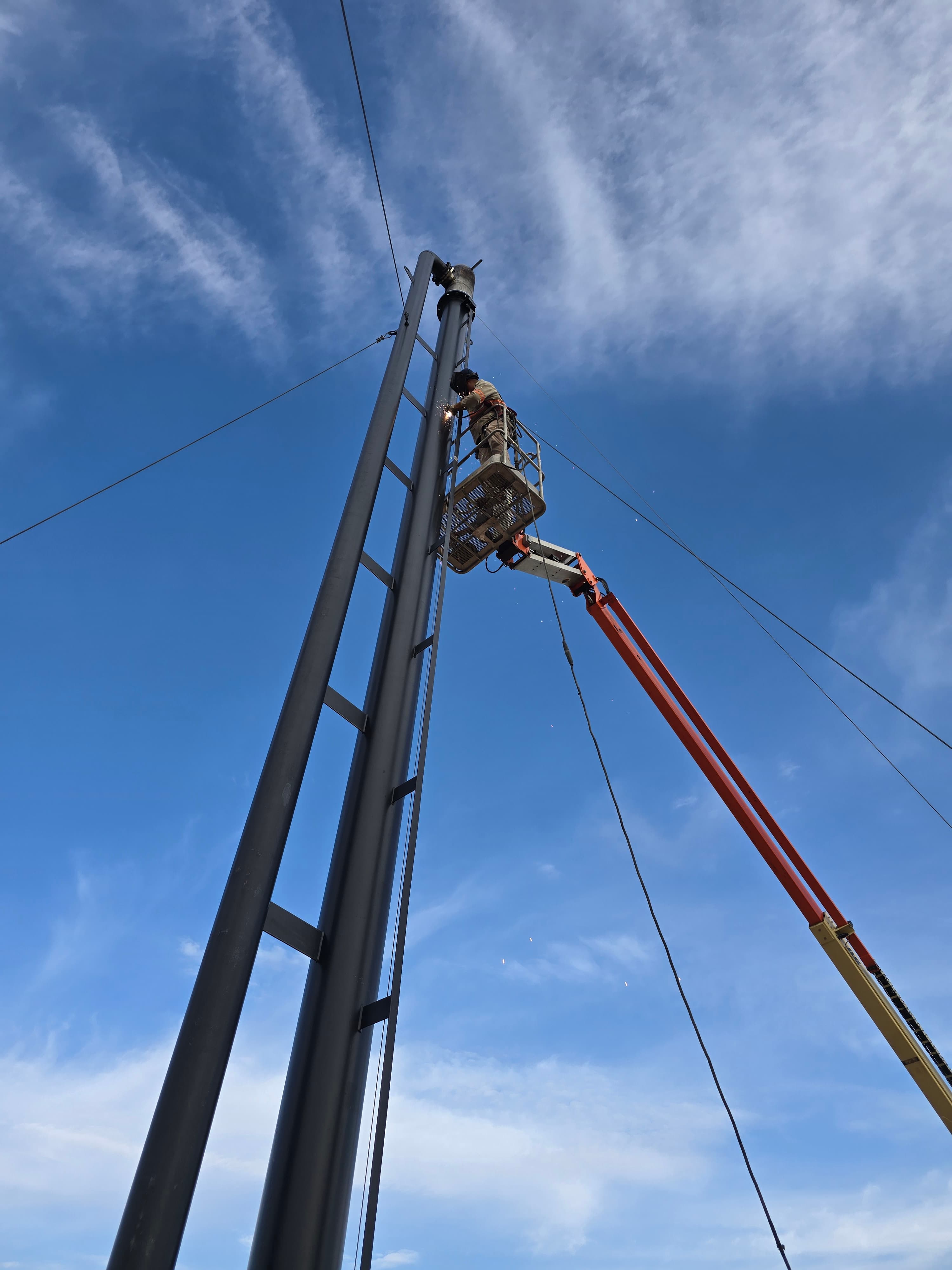 ROS technician welding on a flare stack from a man-lift