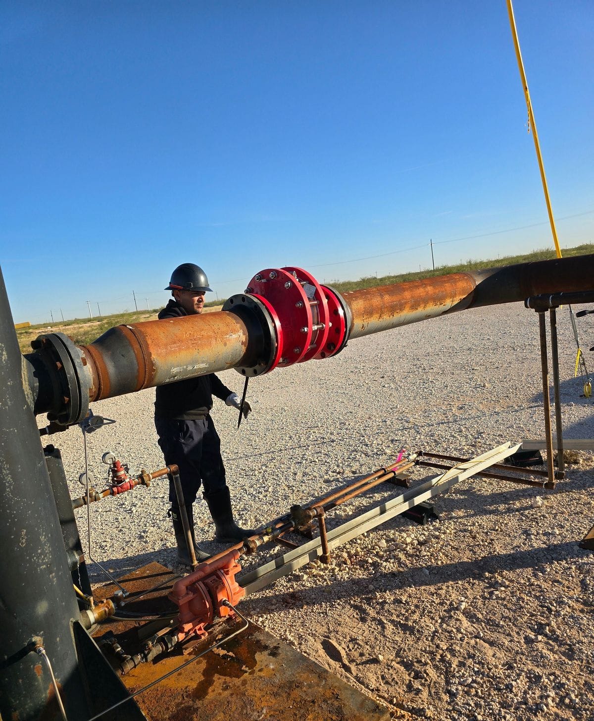 An ROS technician servicing a flame arrestor on a flare line in the Permian Basin