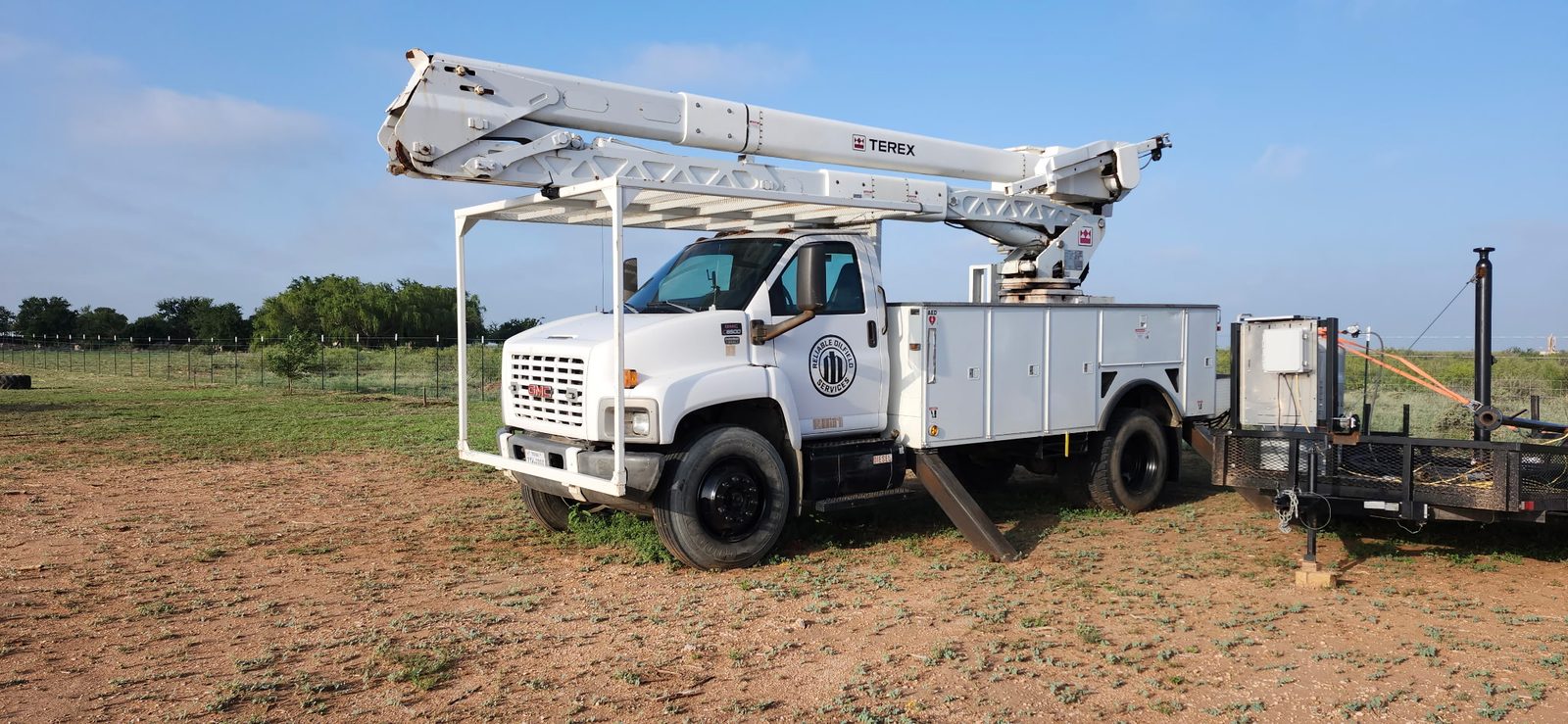 Reliable Oilfield Services bucket truck with the boom raised on a Permian Basin location